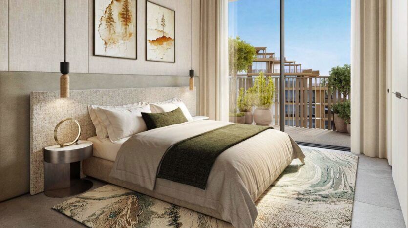 Une chambre à coucher moderne chez Arancia Yards by Beyond comprend un grand lit avec une literie verte et beige, un tableau abstrait au-dessus de la tête de lit, des tables de chevet, des lampes suspendues, un tapis à motifs et des portes vitrées menant à un balcon avec des plantes en pot et des sièges.
