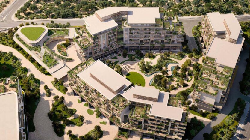 Vue aérienne d'Arancia Yards by Beyond, un complexe d'appartements moderne comprenant plusieurs bâtiments avec des toits verts, des cours paysagées, des allées et des arbres en abondance, le tout entouré de verdure naturelle et de routes.