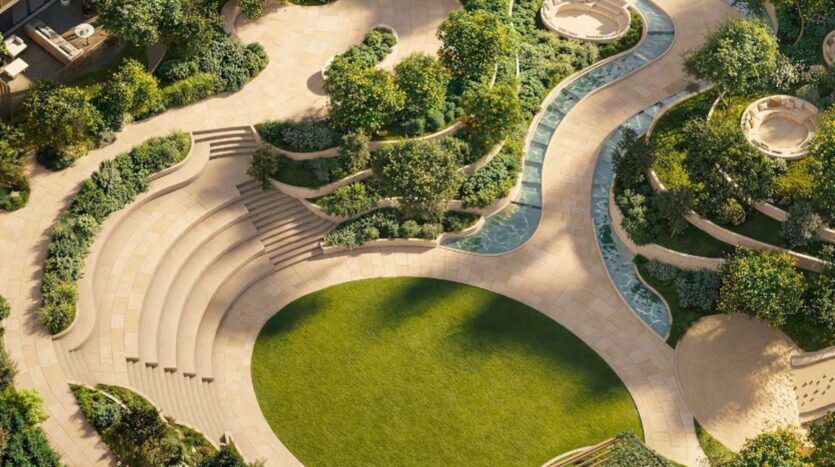Vue aérienne d'Arancia Yards by Beyond, qui présente un jardin paysager avec des allées en pierre incurvées, des marches en terrasse, des arbres verdoyants, une pelouse herbeuse et des plans d'eau étroits qui serpentent à travers la zone.
