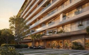 Lunaya Terraces est un immeuble d'appartements moderne de plusieurs étages, doté de grands balcons, d'espaces verts abondants et de baies vitrées. Deux voitures de luxe sont garées devant, tandis que des coins salon en plein air et un aménagement paysager luxuriant entourent le site.