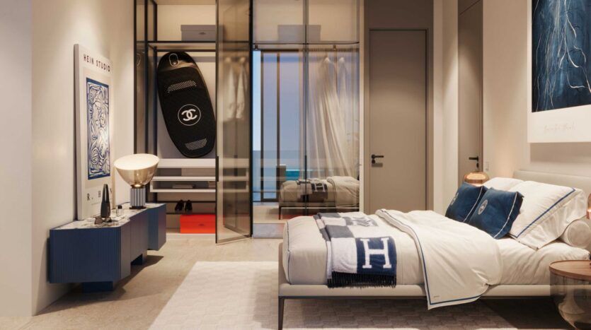 Une chambre à coucher moderne et élégante à la Villa Del Garda avec un lit bien fait, des oreillers et des couvertures de marque, une commode bleue, des œuvres d'art contemporaines et un dressing ouvert avec des articles de marque de luxe. Un éclairage chaleureux crée une atmosphère douillette.