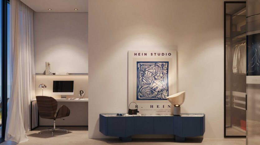 Une chambre moderne et minimaliste de la Villa Del Garda comprend un petit bureau et un ordinateur sur la gauche, une chaise brune et un buffet bleu avec des objets décoratifs sous un grand poster abstrait encadré sur un mur blanc. Un placard est partiellement visible sur la droite.