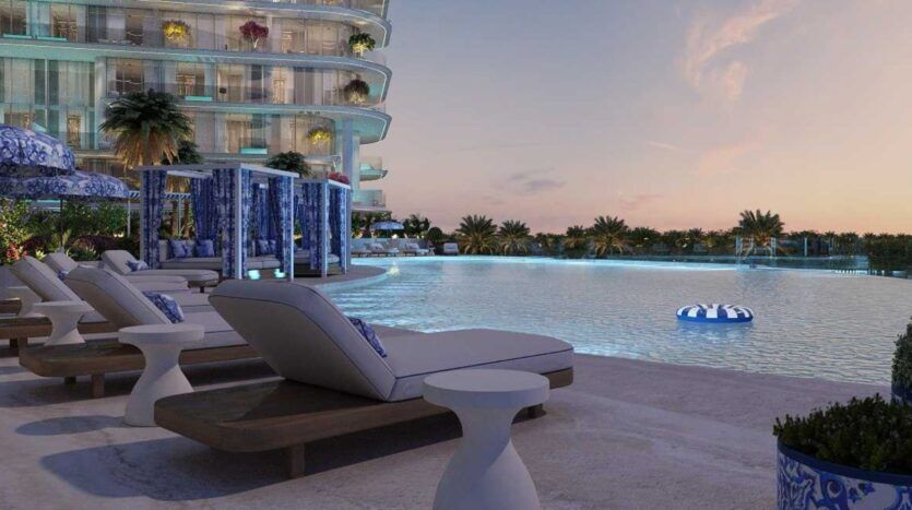 Scène luxueuse au bord de la piscine au coucher du soleil à la Villa Del Garda, avec des chaises longues modernes, des cabanas, un grand bâtiment incurvé, une végétation luxuriante et un anneau gonflable bleu et blanc flottant dans la piscine.