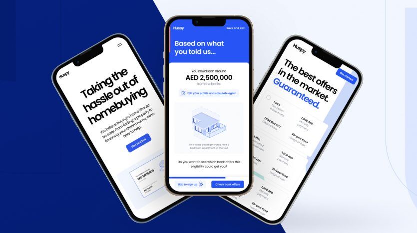 Trois smartphones affichant une interface d'application de crédit immobilier pour l'aide à l'achat d'un logement à Dubaï, avec du texte et des graphiques sur des écrans bleus et blancs, positionnés sur un fond bleu abstrait.