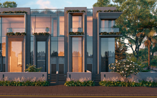 Modernas casas adosadas con ventanas de cristal reflectante y jardines verticales integrados en la fachada. A medida que el sol poniente proyecta un cálido resplandor, resaltando el cuidado paisajismo salpicado de una variedad de árboles y arbustos, esto ilustra