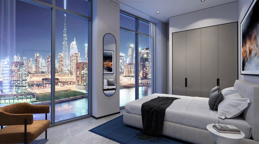 Intérieur d'une chambre moderne du 15ème côté nord la nuit avec de grandes fenêtres montrant un horizon urbain animé. La chambre dispose d'un lit, d'une chaise en bois et d'une décoration minimaliste.