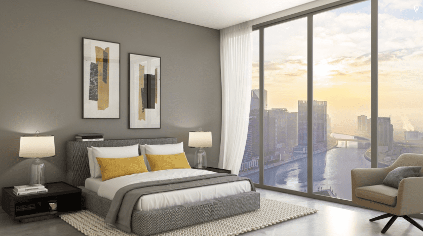 Chambre moderne avec une grande fenêtre donnant sur le magnifique paysage urbain de Dubaï au coucher du soleil, comprenant un lit double, deux lampes de chevet, des œuvres d'art murales abstraites et un coin salon confortable.