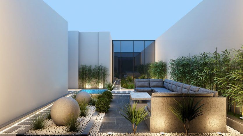 Cour moderne au crépuscule avec une piscine rectangulaire, un aménagement paysager minimaliste avec des galets et des plantes vertes, un canapé sectionnel gris et une façade de bâtiment élégante avec du verre réfléchissant au Prime Residency 3.