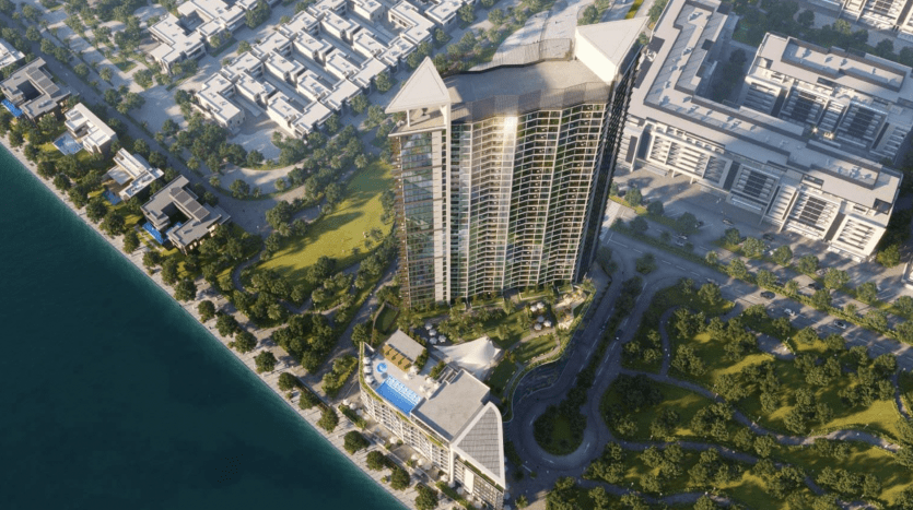 Vue aérienne d'un immeuble moderne de grande hauteur, Waves Grande, doté d'un toit unique en forme d'aile, entouré de parcs verts et situé à proximité d'un plan d'eau, avec d'autres bâtiments urbains dans le