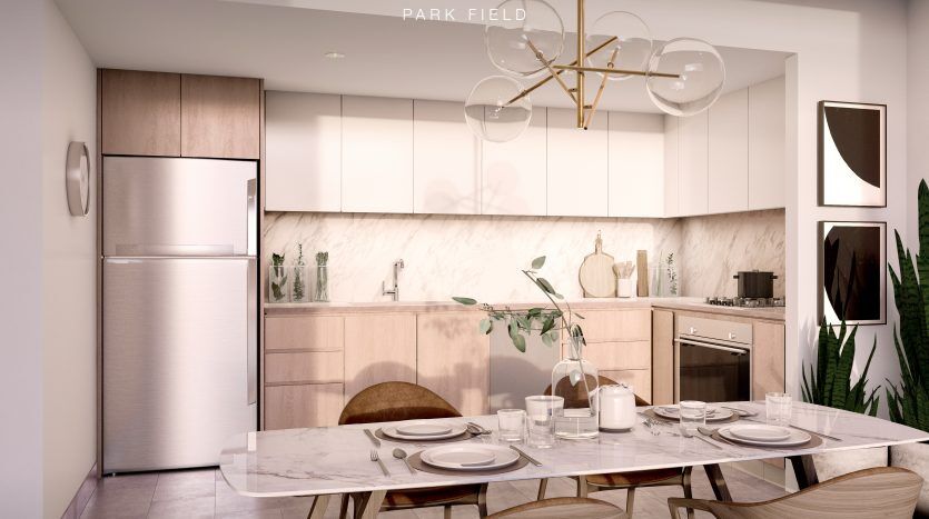Cuisine moderne avec armoires en bois clair, dosseret en marbre élégant et coin repas attenant avec une table en bois pour deux personnes, sous un luminaire unique. Le texte indique « Collines de Dubaï