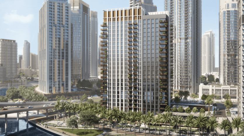 Des bâtiments modernes, dont de hautes tours résidentielles avec balcons, surplombant un canal et un parc paysager avec des sentiers pédestres et des palmiers, dans le quartier animé de Dubaï.