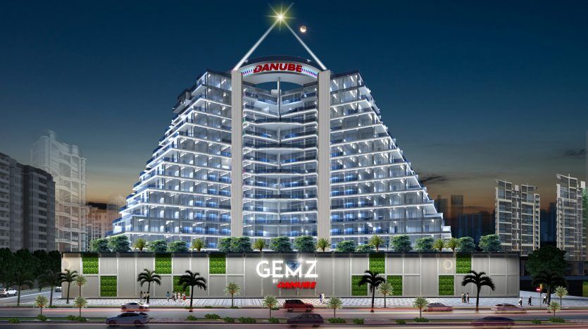 Rendu numérique d'une villa moderne de grande hauteur à Dubaï avec des fenêtres éclairées au crépuscule, avec une signalisation bien visible pour "danube" et "gemz by danube". Verdure luxuriante et scène de rue animée
