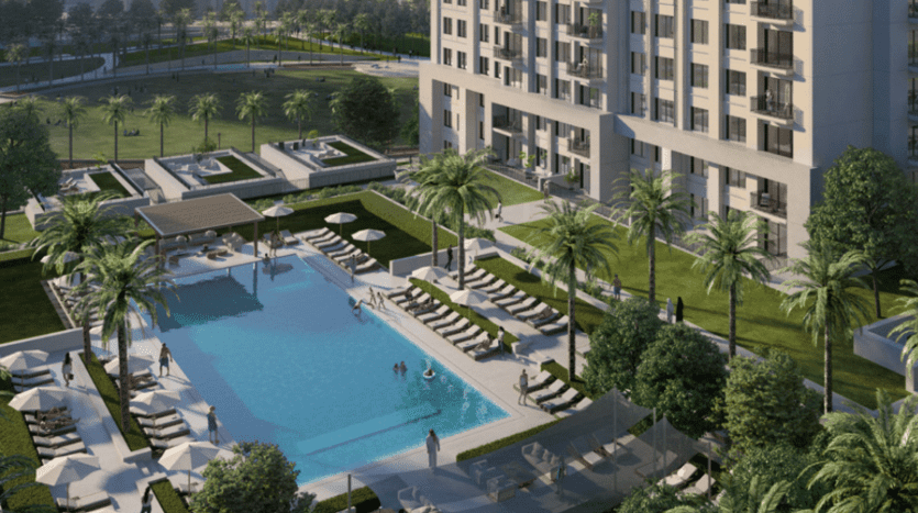 Un luxueux immeuble d'appartements de grande hauteur à Dubaï surplombant une grande piscine entourée de chaises longues et de verdure luxuriante, situé dans un environnement paysager serein au crépuscule.