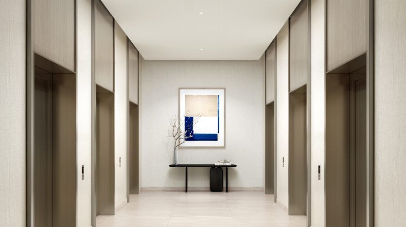 Un couloir intérieur moderne et élégant au design symétrique avec des murs beiges, un éclairage lumineux et des œuvres d'art encadrées au bout, situé à Hills Park, Dubai Hills Estate by Emaar, un excellent exemple