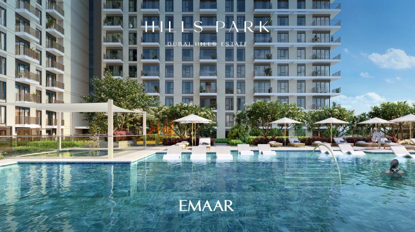 Luxueuse piscine extérieure dans le parc des collines du Dubai Hills Estate avec chaises longues et parasols, entourée d'un immeuble résidentiel moderne de grande hauteur, parfaite pour les investissements immobiliers de Dubaï.