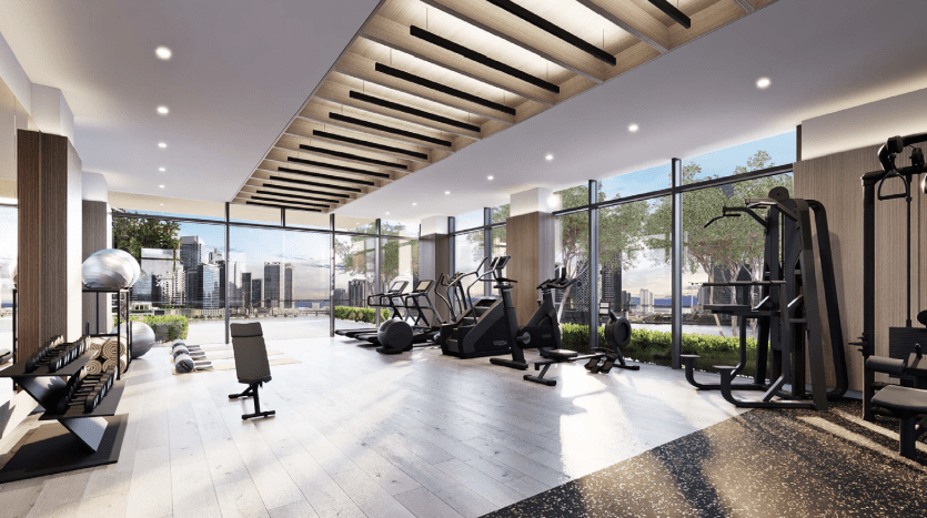 Salle de sport moderne avec divers appareils d'exercice, notamment des tapis roulants et des stations de musculation, donnant sur un paysage urbain à travers de grandes fenêtres dans un appartement de Dubaï. Intérieur lumineux avec poutres en bois au plafond et sol réfléchissant.