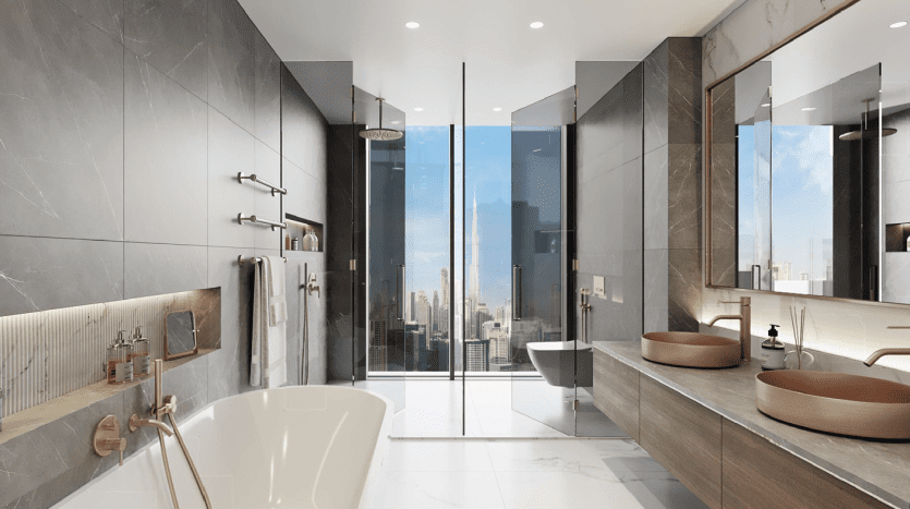 Salle de bain moderne comprenant une baignoire autoportante, deux lavabos avec vasques marron, de grands miroirs et une douche en verre, le tout donnant sur un paysage urbain à travers des baies vitrées dans un appartement de Dubaï