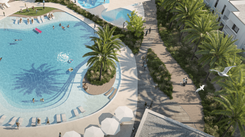 Aerial view of a lively swimming pool surrounded by palm trees and walkways with people enjoying various activities such as swimming and sunbathing in Dubai.