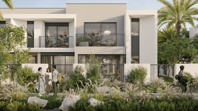 Modern residential villa in Dubai with white facades, large windows and balconies, set amid lush gardens. People walk and cycle along a path in the foreground.