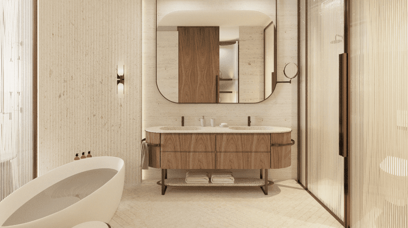 Une salle de bains contemporaine dans un appartement de Dubaï comprenant une baignoire îlot, une vasque en bois avec un miroir rond et des murs texturés, baignés d'un éclairage d'ambiance chaleureux.