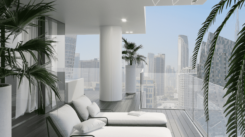 Salon moderne et minimaliste avec d'élégants canapés blancs et une table basse noire, entouré de grandes plantes en pot. Les murs de verre offrent une vue panoramique sur les toits de Dubaï.