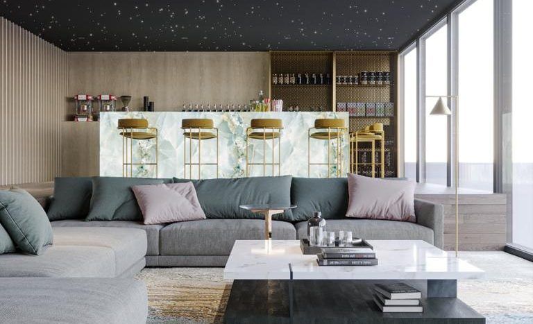 Un salon moderne dans un appartement de Dubaï avec un plafond étoilé, un grand canapé sectionnel gris, une table basse blanche et de hautes fenêtres à côté d'un bar élégant.