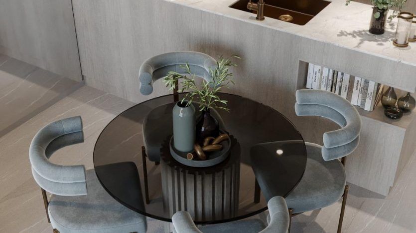 Une cuisine moderne dans une villa de Dubaï avec une table à manger ronde et quatre chaises bleues courbées autour. La table comporte un vase central avec de la verdure. La cuisine est dotée d'armoires en bois, d'électroménagers encastrés,