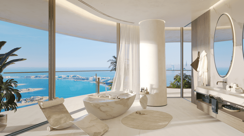 Salle de bains luxueuse aux finitions en marbre, dotée d'une baignoire autoportante, d'une double vasque et de baies vitrées donnant sur une vue sereine sur l'océan, parfaite pour ceux qui cherchent à investir dans l'immobilier à Dubaï.