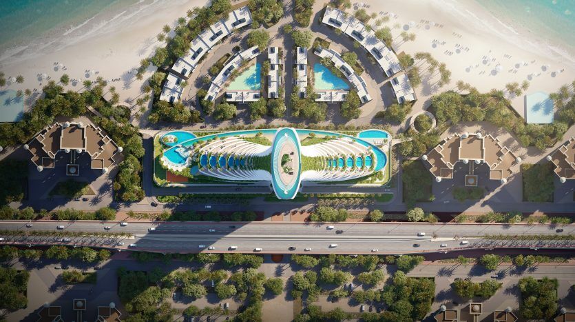 Vue aérienne d'un complexe hôtelier de luxe au bord de la plage de Dubaï, doté d'une piscine centrale de forme ovale entourée de blocs hôteliers en forme de croissant et d'une verdure luxuriante, bordée par une route et alignée avec le