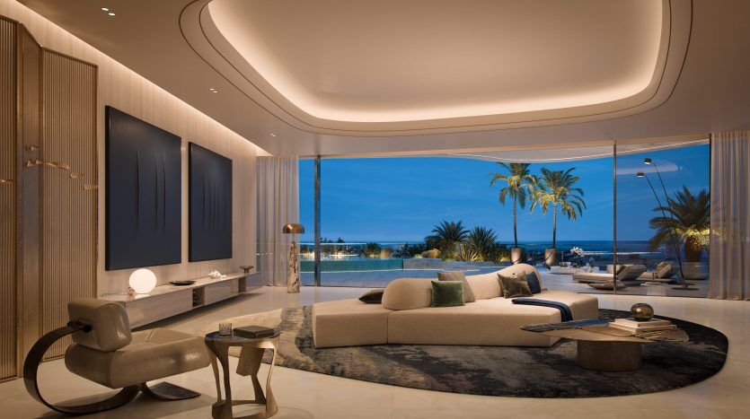Salon luxueux dans une villa de Dubaï avec une décoration moderne, de grands canapés et des baies vitrées donnant sur une plage tropicale au crépuscule. Un éclairage doux et un mobilier élégant rehaussent l'ambiance sereine.