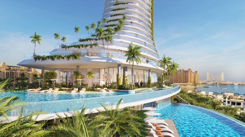 Une luxueuse station balnéaire de Dubaï dotée d'un bâtiment blanc curviligne, de vastes piscines extérieures, de palmiers et de chaises longues, avec une ligne d'horizon de la ville en arrière-plan sous un ciel bleu clair.