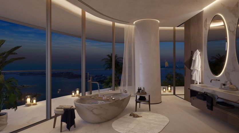 Salle de bain luxueuse dans un appartement de Dubaï avec une baignoire îlot donnant sur un paysage marin nocturne à travers des baies vitrées, entourée de bougies et un décor élégant et moderne.