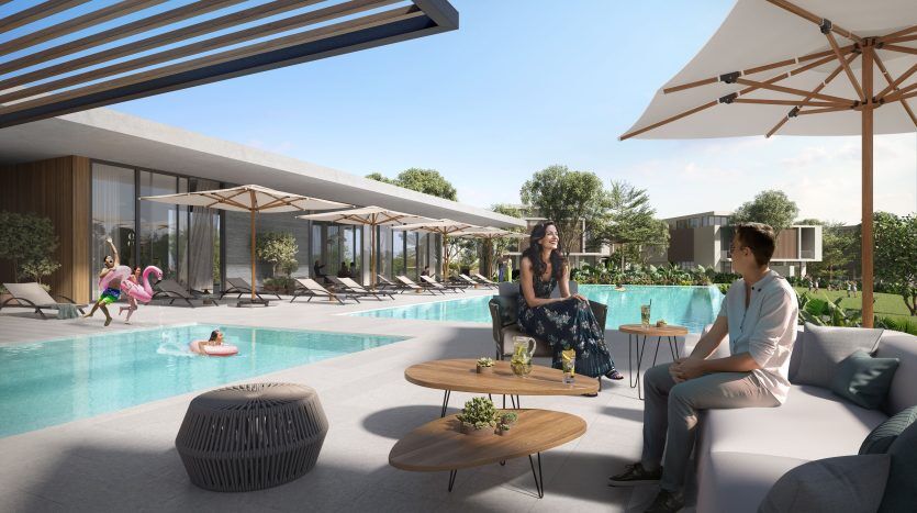 Une scène luxueuse au bord de la piscine dans une propriété exclusive de l'immobilier Dubaï, mettant en vedette une femme et un homme assis et discutant. Chaises longues, parasols et autres personnes profitant de la journée ensoleillée en arrière-plan