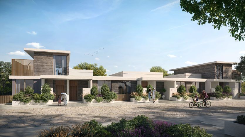Complexe résidentiel moderne avec toits plats, grandes fenêtres et revêtement extérieur en bois et en pierre. Des gens faisant du vélo et assis dans la cour ensoleillée et paysagée avec une verdure luxuriante dans un prestigieux immobilier de Dubaï