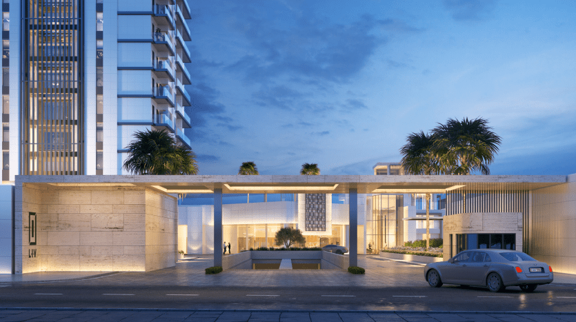 Une luxueuse entrée de villa moderne à Dubaï au crépuscule, avec des murs en pierre illuminés, des palmiers, un plan d'eau réfléchissant et une voiture garée.
