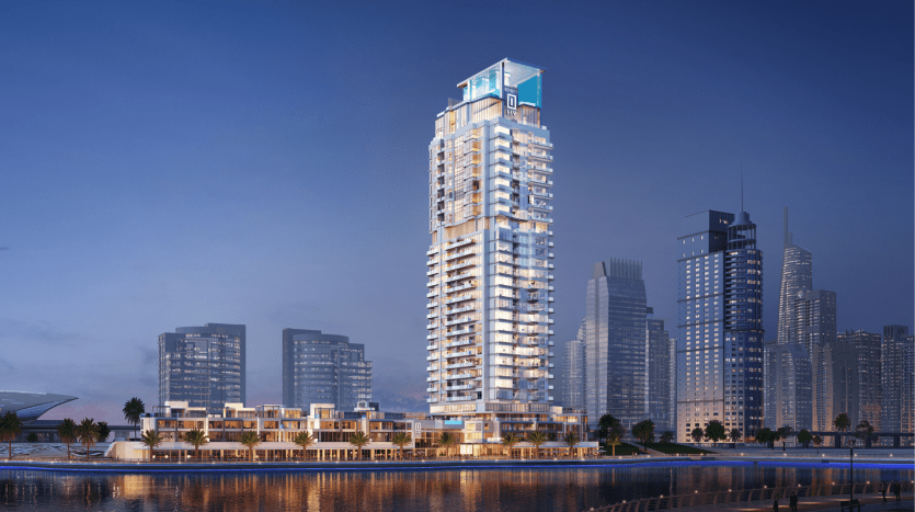 Un immeuble résidentiel moderne de grande hauteur illuminé au crépuscule avec en toile de fond un paysage urbain et une eau réfléchissante au premier plan à Dubaï.