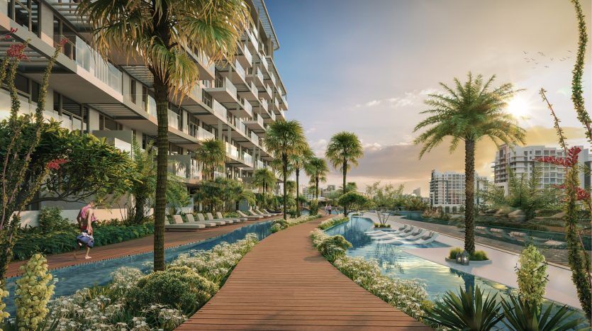 Complexe résidentiel luxuriant à Dubaï comprenant des appartements modernes avec de grands balcons donnant sur une paisible rivière artificielle, entourés de palmiers et de jardins florissants.