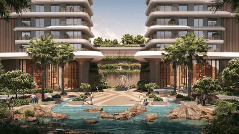 La façade d'un hôtel de luxe comprend deux bâtiments modernes de plusieurs étages aux lignes courbes et aux grandes fenêtres. Une cour centrale au design géométrique mène à une piscine sereine accentuée par des éléments rocheux et un aménagement paysager luxuriant de Verdes, comprenant de grands palmiers et d'autres espaces verts.