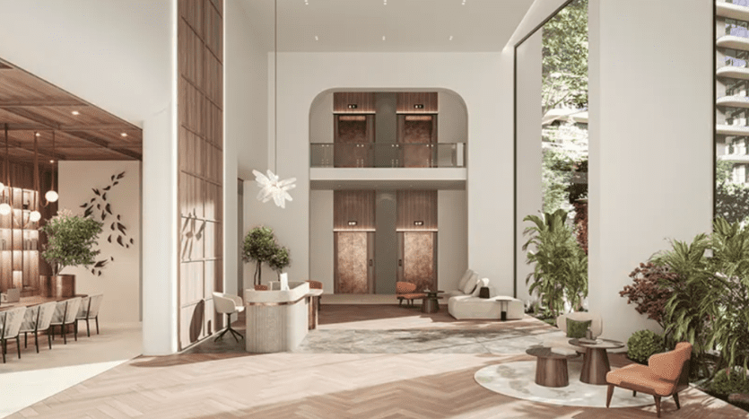Lobby spacieux et moderne avec de hauts plafonds, de grandes fenêtres et un mélange de tons ocre. Les caractéristiques comprennent un petit bureau de réception, des coins salons avec des chaises et des tables, des plantes vertes intérieures luxuriantes, deux ascenseurs et une salle à manger bien éclairée avec une longue table et des suspensions.