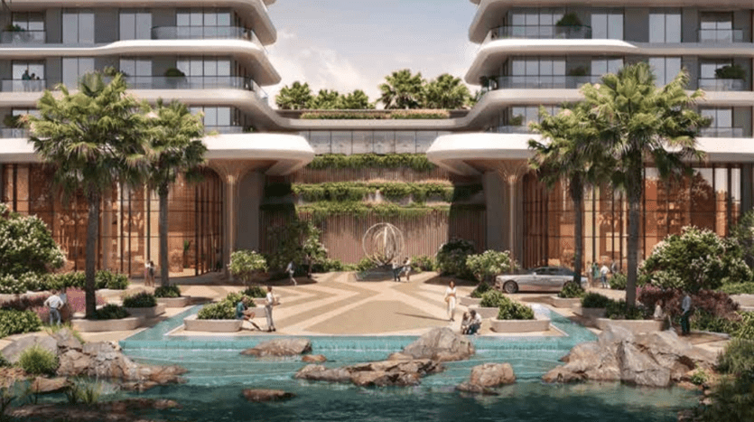 Des bâtiments modernes et luxueux dotés de grands balcons flanquent les deux côtés d'une cour centrale dotée d'une verdure luxuriante, de palmiers et d'une fontaine géométrique. Une voiture est garée sous l'entrée couverte et les gens marchent et s'assoient près de l'eau turquoise de Verdes entourée de rochers.