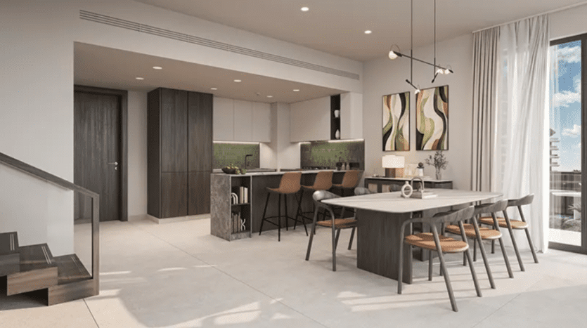 Cuisine et salle à manger modernes à aire ouverte avec un décor minimaliste. L'espace comprend une cuisine élégante avec des armoires en bois sombre, un îlot de cuisine avec des tabourets de bar et une longue table à manger avec des chaises en bois. Les grandes fenêtres laissent entrer la lumière naturelle, mettant en valeur les œuvres d'art modernes et les accents verts vibrants.