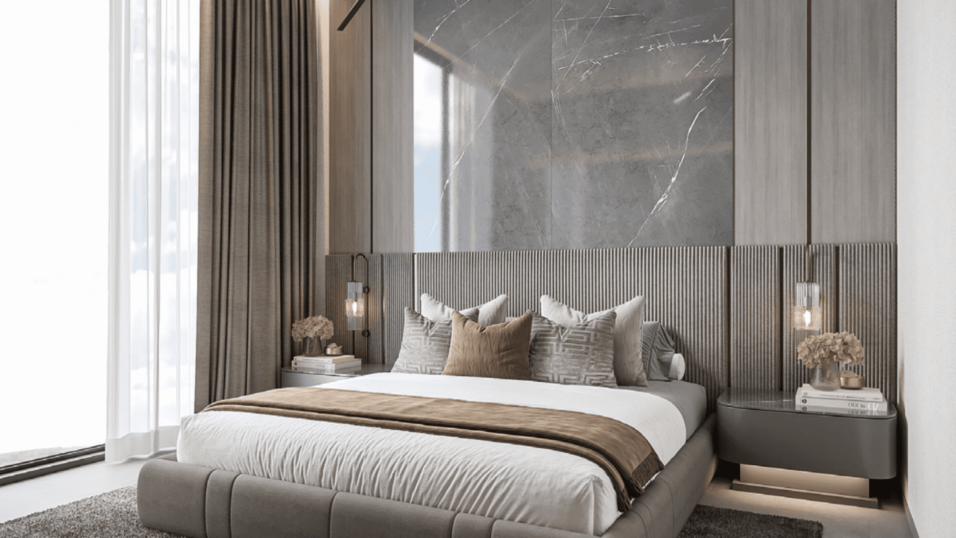 Une chambre moderne au One Park Square dispose d'un grand lit rembourré orné d'oreillers assortis et d'une couverture marron. Les murs en marbre et les luminaires suspendus rehaussent son élégance, tandis que les fenêtres du sol au plafond avec des rideaux transparents invitent une lumière naturelle abondante.
