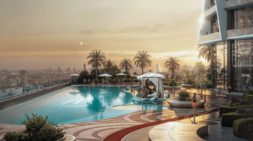 Une luxueuse piscine sur le toit, au coucher du soleil, avec des palmiers, des cabanas, des chaises longues et une vue sur la ligne d'horizon de la ville. Une personne se promène près de la piscine, tandis que d'autres se détendent sous des auvents blancs. La scène respire la détente et l'élégance.