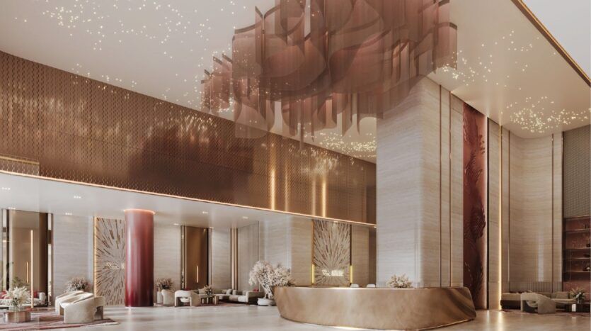 Le luxueux hall d'entrée de l'hôtel présente de hauts plafonds, un élégant décor or et crème, un lustre sculptural, un bureau de réception moderne, des sièges moelleux et de grands piliers, reflétant l'ambiance sophistiquée du design emblématique du Binghatti Skyblade.