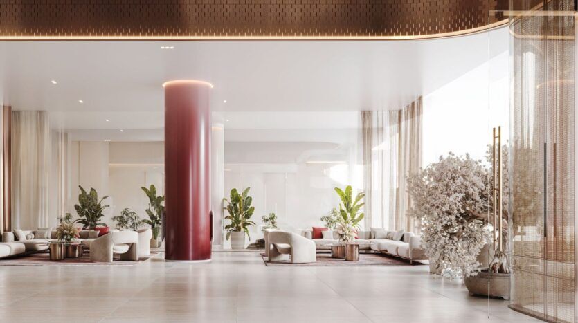 Le hall d'entrée moderne et spacieux du Binghatti Skyblade se caractérise par une colonne rouge brillante, des canapés de couleur claire, des plantes d'intérieur, des rideaux diaphanes et de grandes fenêtres qui inondent l'espace de lumière naturelle. Des tons neutres et un mobilier élégant et minimal complètent l'ensemble.