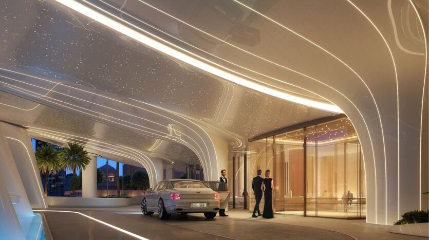 Une voiture de luxe s'arrête devant l'entrée futuriste du Binghatti Skyblade, avec son architecture incurvée, ses lumières brillantes et ses personnes en tenue de soirée près des portes vitrées. Des palmiers se balancent à l'extérieur de cet emblème moderne.