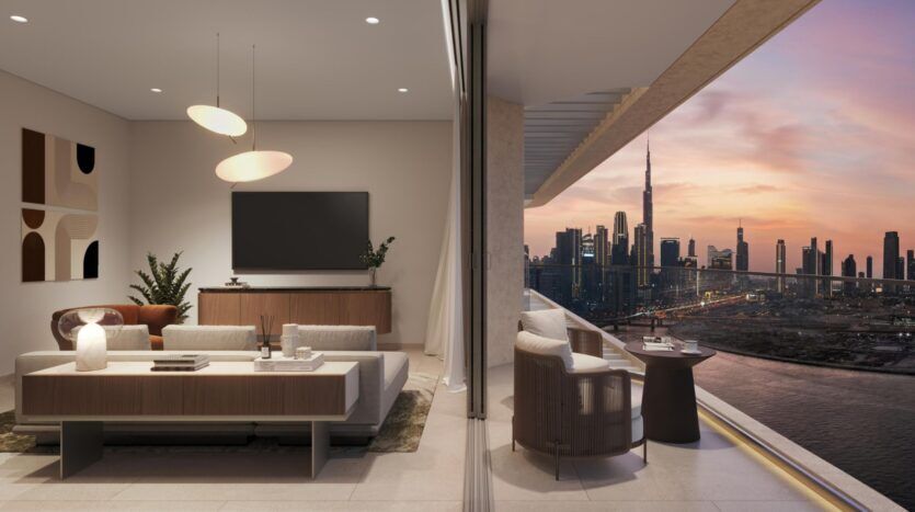 Le salon moderne aux tons neutres s'ouvre sur un balcon qui donne sur la ville au coucher du soleil, avec les gratte-ciel et le Burj Khalifa. L'espace intérieur met en valeur l'art avec un canapé élégant, des œuvres d'art, une télévision, des plantes et des lampes suspendues.