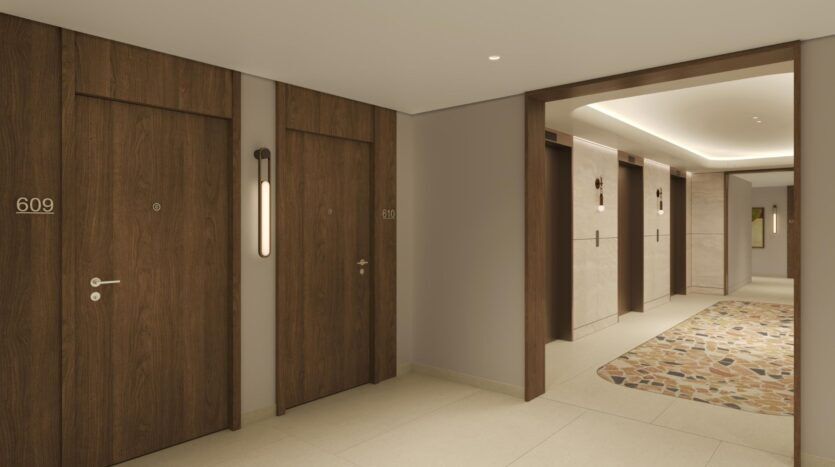 Couloir d'un hôtel moderne avec des portes en bois marquées 609 et 610, des murs beiges, une moquette à motifs et un éclairage encastré au plafond. Trois portes d'ascenseur sont visibles à l'arrière-plan, alliant l'art à une atmosphère propre et tranquille.