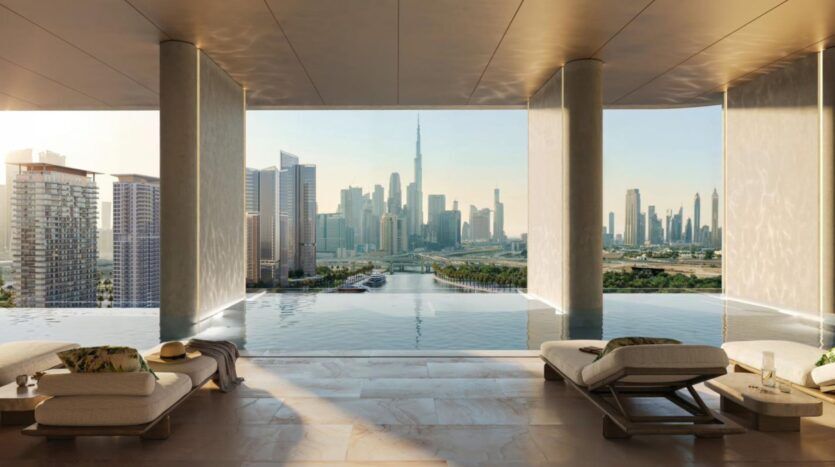 Une luxueuse piscine intérieure à débordement avec des chaises longues donne sur la ligne d'horizon de la ville avec le Burj Khalifa, où la lumière du soleil pénètre à flots et où l'art du design moderne crée une atmosphère sereine sous un ciel dégagé.