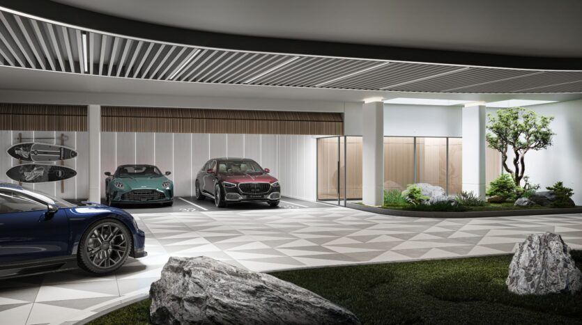 Un parking intérieur moderne présentant Bella by Passo, avec trois voitures de luxe garées, des planches de surf fixées au mur, des carreaux de sol géométriques, une entrée vitrée et un espace vert aménagé avec des rochers et un petit arbre.